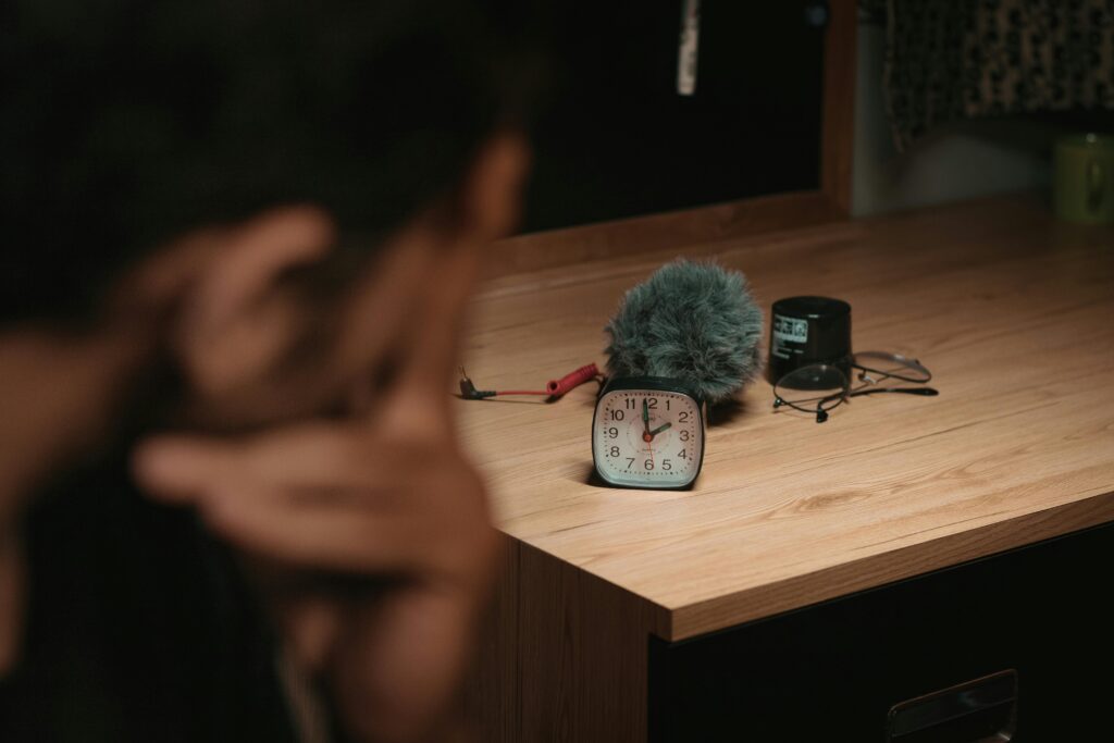 Wooden desk with a clock, wind muff, and recording gear, captured indoors.