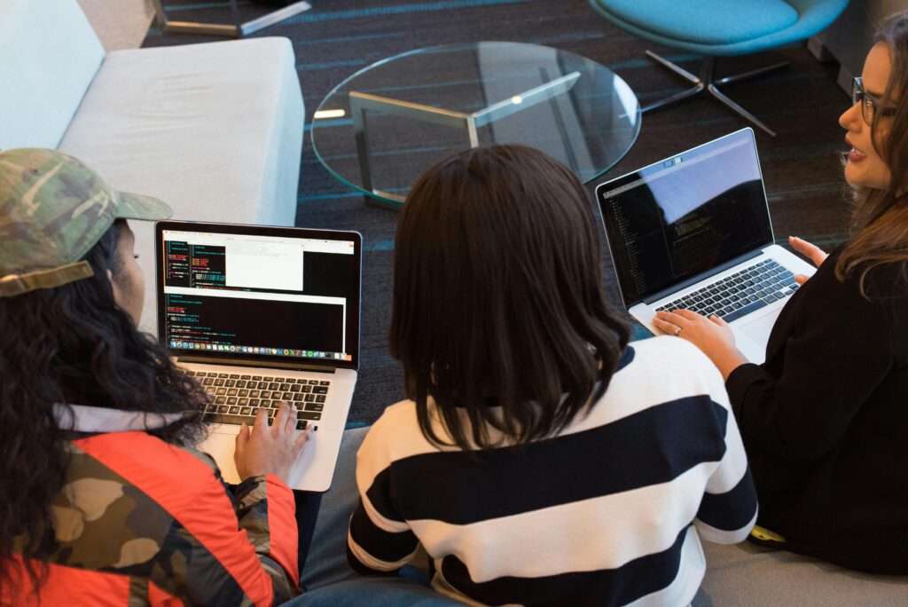 Three women working on laptops in a stylish office, focused on a collaborative project.