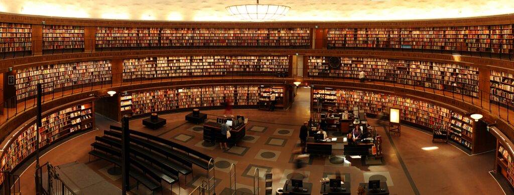 Panoramic view of a grand circular library with shelves full of books and study desks.