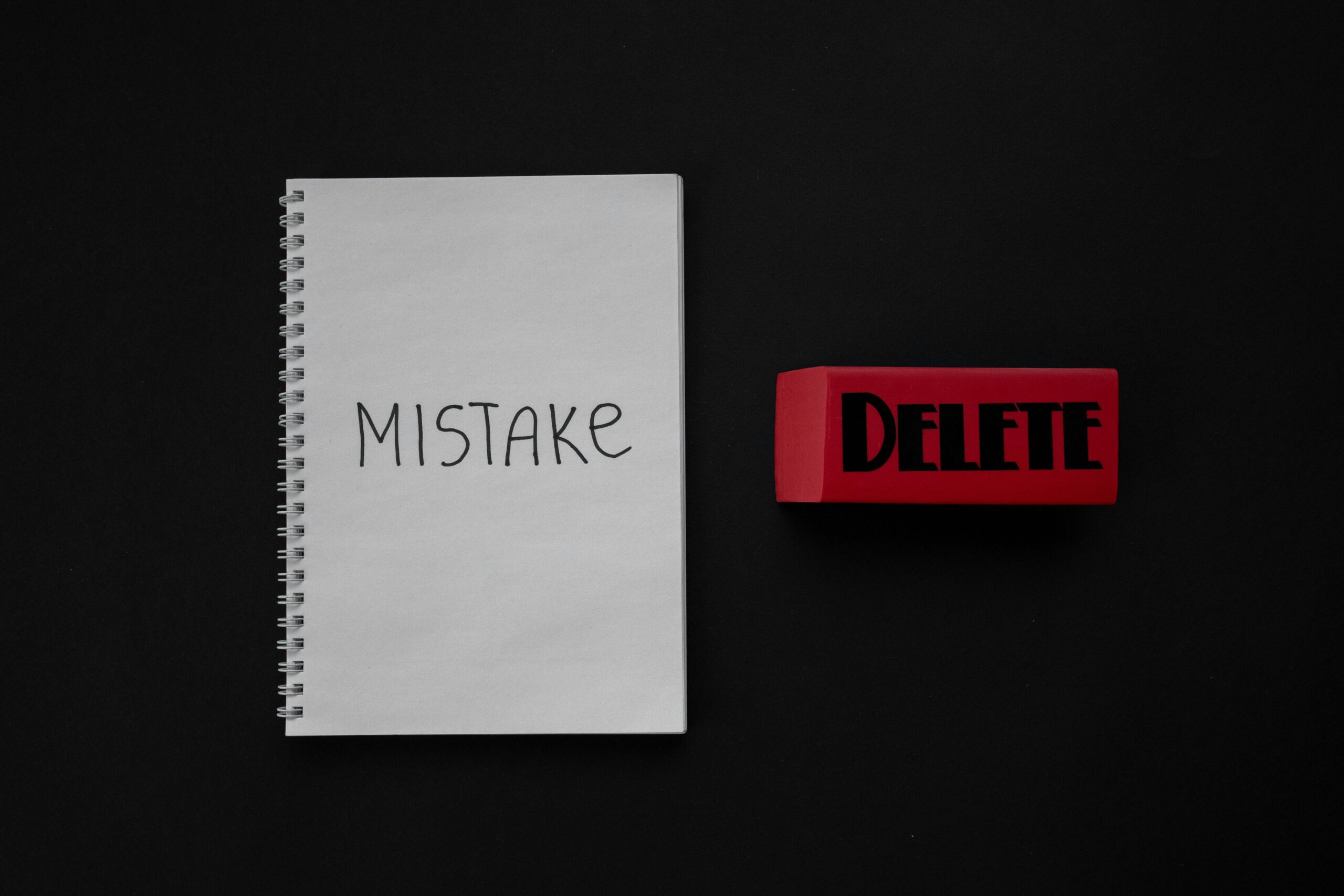 Notebook labeled 'Mistake' next to a red delete eraser on a dark background.