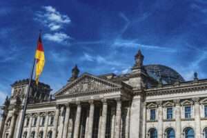 Historic Reichstag in Berlin under a vibrant blue sky, featuring the German flag.